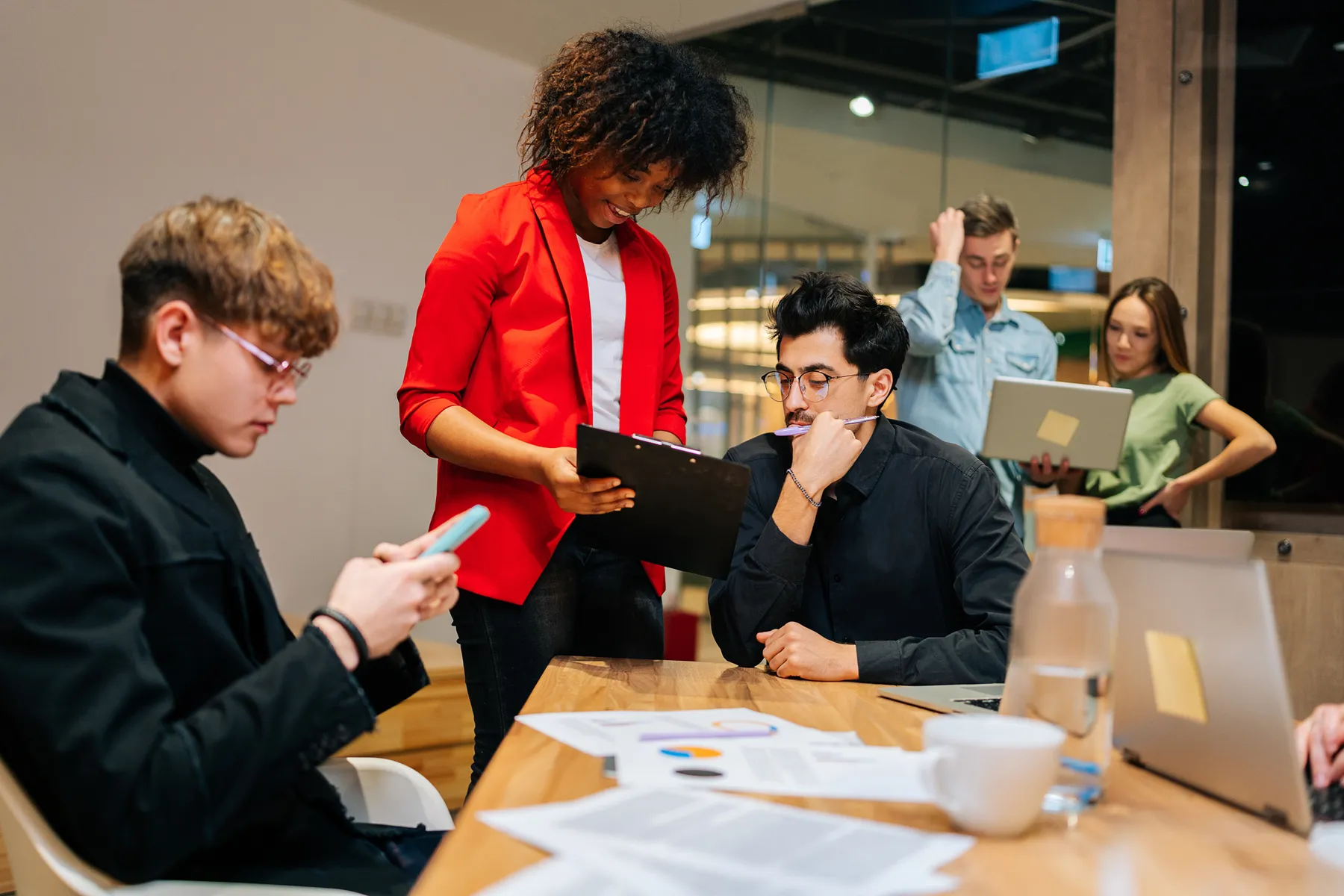 team leader checking document from colleague in office surrounded by startup team